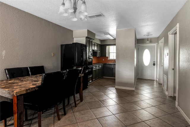 kitchen with tile patterned floors, black refrigerator, a textured ceiling, and an inviting chandelier