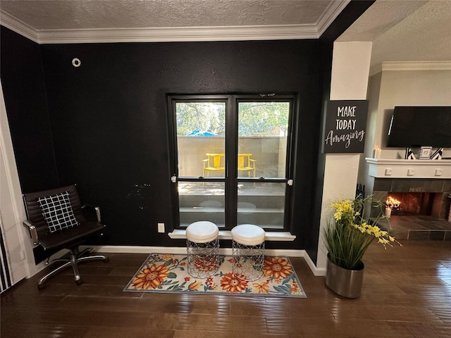 living area with dark hardwood / wood-style flooring, ornamental molding, a textured ceiling, and a tiled fireplace