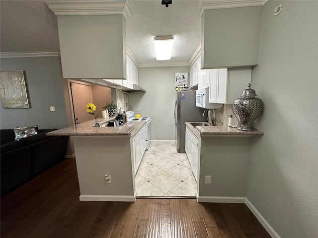 kitchen featuring light hardwood / wood-style flooring, kitchen peninsula, white appliances, white cabinets, and ornamental molding