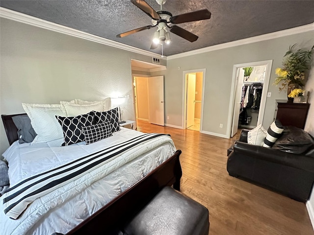 bedroom featuring ceiling fan, a spacious closet, a textured ceiling, ornamental molding, and a closet