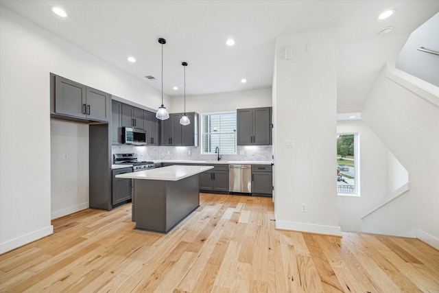 kitchen featuring a center island, light hardwood / wood-style floors, backsplash, pendant lighting, and appliances with stainless steel finishes