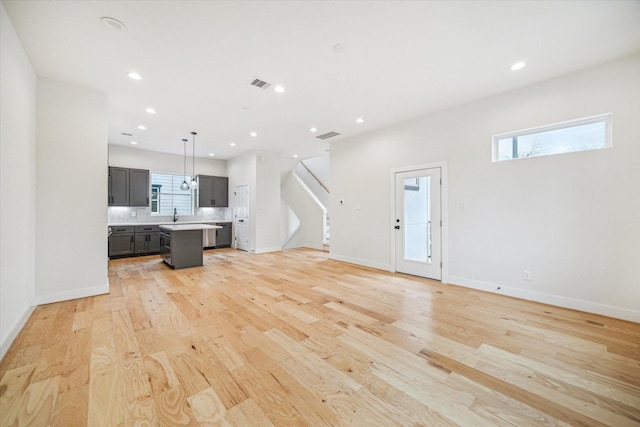 unfurnished living room with sink and light wood-type flooring