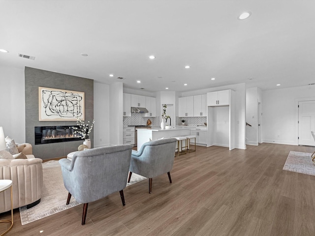 living room with a tile fireplace, light hardwood / wood-style flooring, and sink