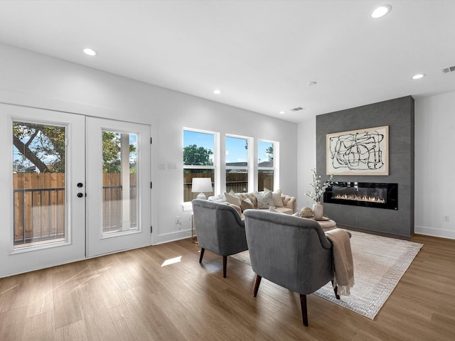 living room with hardwood / wood-style floors, a large fireplace, and french doors