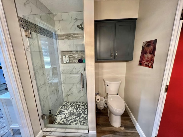 bathroom featuring hardwood / wood-style floors, toilet, and a shower with door