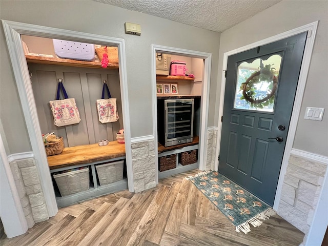 mudroom with a textured ceiling, wine cooler, and light parquet flooring