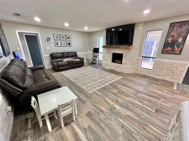 living room with hardwood / wood-style flooring, a fireplace, and a textured ceiling