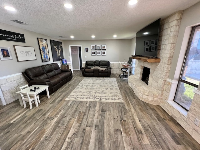 living room with a fireplace, wood-type flooring, and a textured ceiling