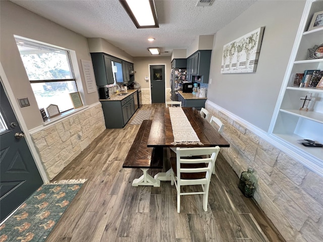 dining space with built in shelves, a textured ceiling, dark hardwood / wood-style floors, and sink