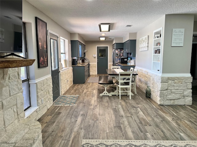 interior space with built in shelves, sink, wood-type flooring, and a textured ceiling