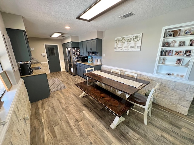 dining space featuring light hardwood / wood-style floors, built in features, and a textured ceiling