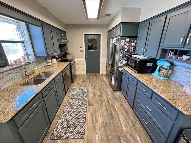 kitchen with decorative backsplash, sink, and light stone counters