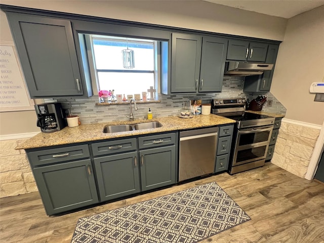 kitchen featuring light stone countertops, sink, light hardwood / wood-style flooring, backsplash, and appliances with stainless steel finishes