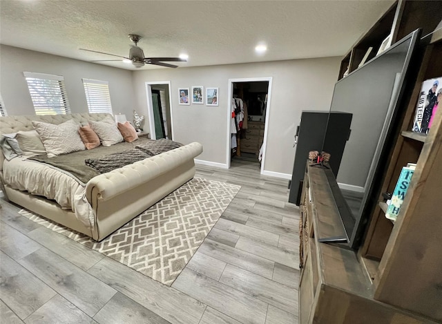 bedroom with a textured ceiling, a closet, a spacious closet, and ceiling fan