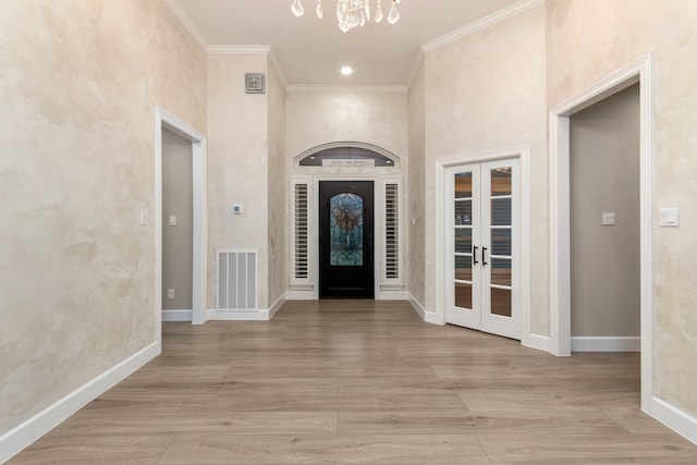 entryway with an inviting chandelier, ornamental molding, and french doors