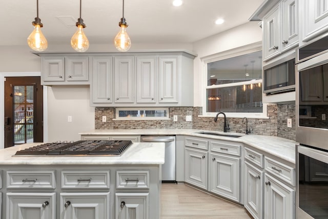 kitchen featuring sink, a center island, hanging light fixtures, stainless steel appliances, and decorative backsplash