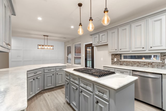 kitchen with gray cabinetry, light wood-type flooring, decorative light fixtures, a kitchen island, and stainless steel appliances