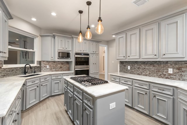 kitchen featuring a center island, stainless steel appliances, gray cabinetry, and sink