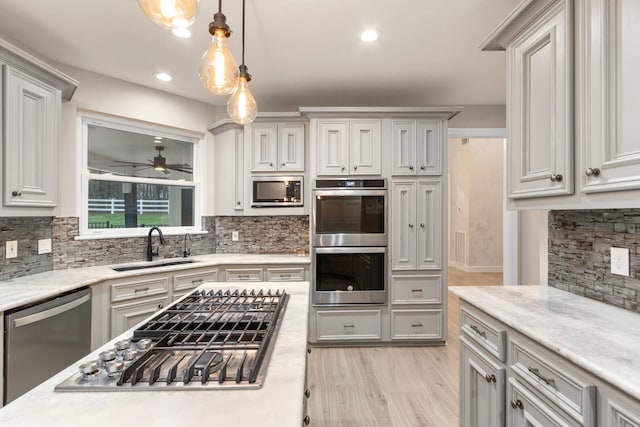 kitchen featuring backsplash, sink, ceiling fan, decorative light fixtures, and stainless steel appliances