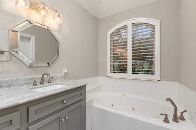 bathroom with a washtub, vanity, and lofted ceiling