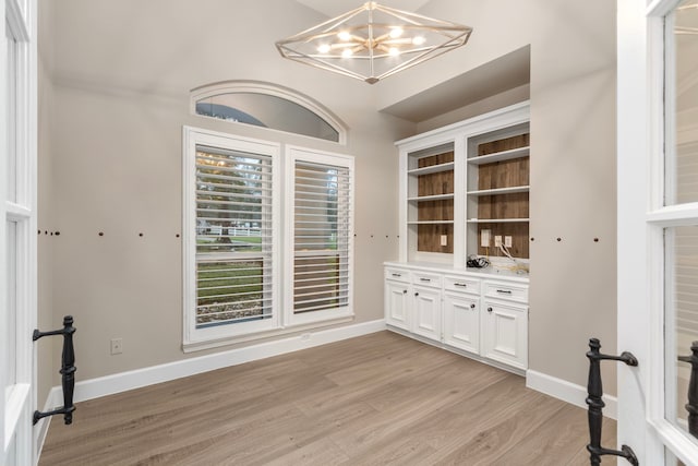 unfurnished dining area featuring light hardwood / wood-style floors and an inviting chandelier