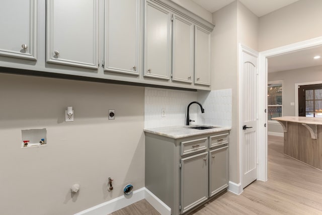 washroom with cabinets, gas dryer hookup, sink, hookup for a washing machine, and light hardwood / wood-style flooring