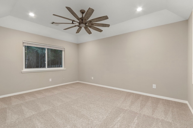 empty room with a tray ceiling, ceiling fan, and light colored carpet