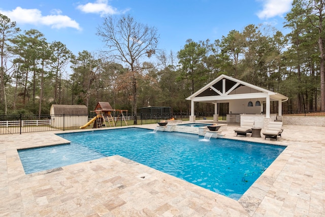 view of swimming pool featuring pool water feature, a playground, an in ground hot tub, and a patio