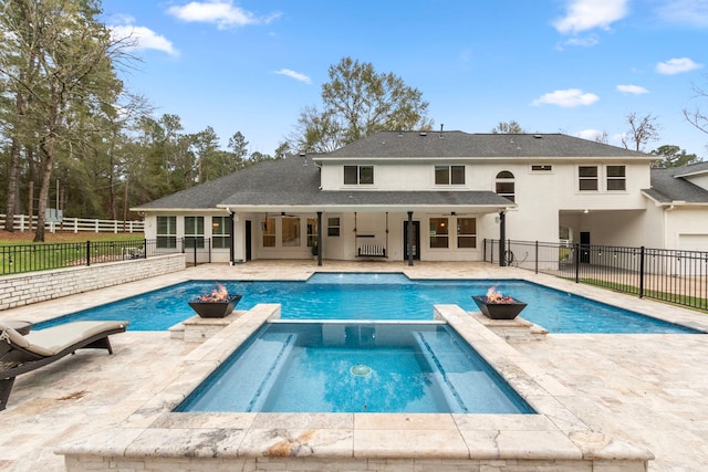 back of property with ceiling fan, a swimming pool with hot tub, and a patio