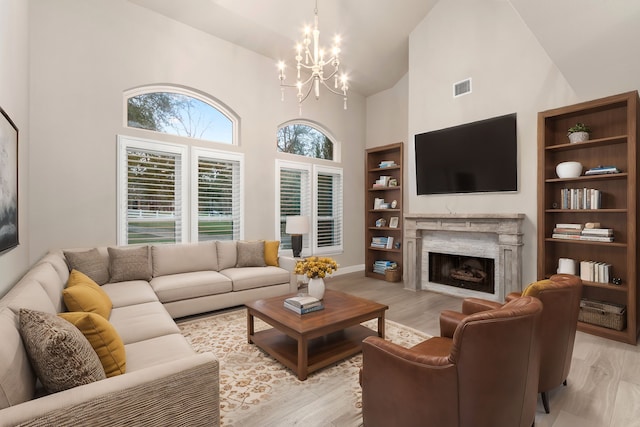 living room with a fireplace, a towering ceiling, and light wood-type flooring