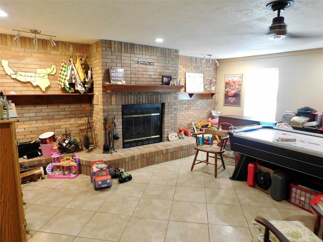 playroom with brick wall, a brick fireplace, tile patterned floors, and rail lighting