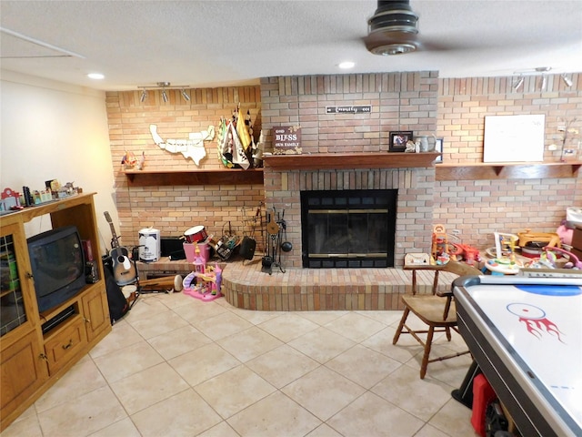 living room featuring brick wall, light tile patterned flooring, a textured ceiling, and a fireplace