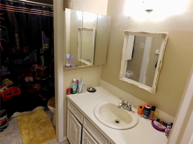 bathroom with toilet, vanity, and tile patterned flooring