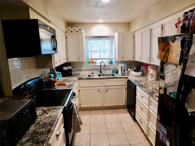 kitchen featuring black appliances, a textured ceiling, light stone counters, white cabinets, and sink