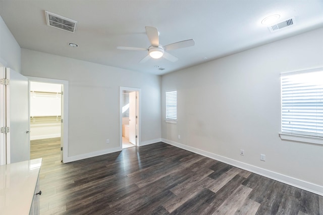 unfurnished bedroom featuring a walk in closet, ensuite bath, ceiling fan, multiple windows, and a closet