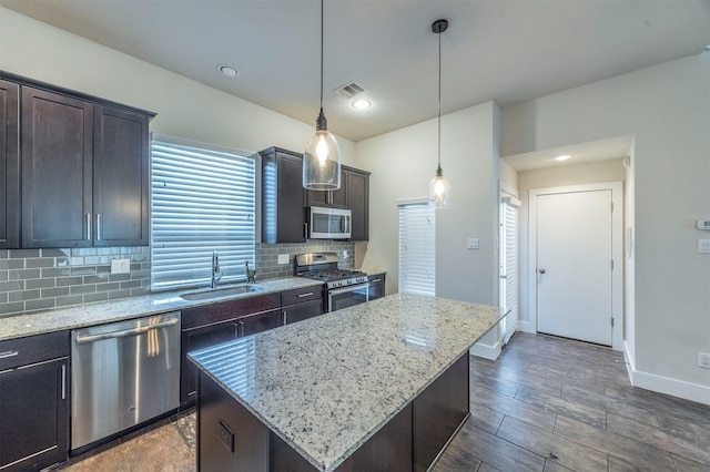 kitchen featuring sink, a kitchen island, hanging light fixtures, and appliances with stainless steel finishes