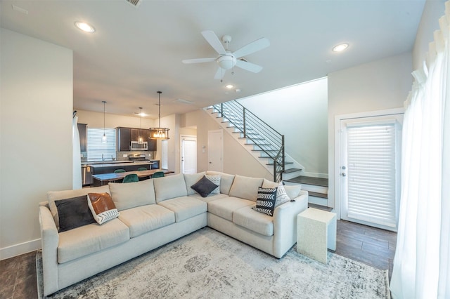 living room featuring ceiling fan with notable chandelier, plenty of natural light, and light wood-type flooring