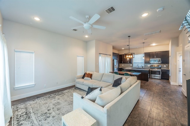 living room with ceiling fan with notable chandelier