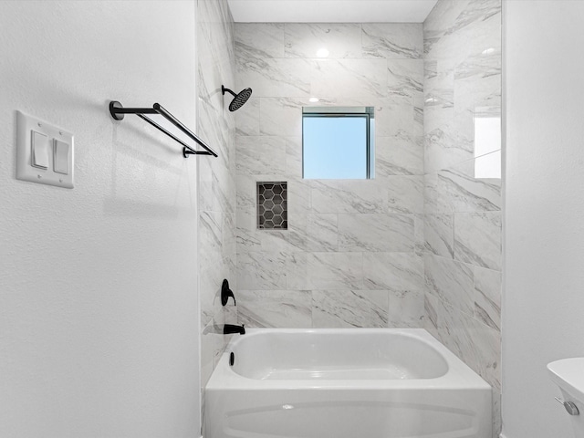 bathroom featuring toilet and tiled shower / bath