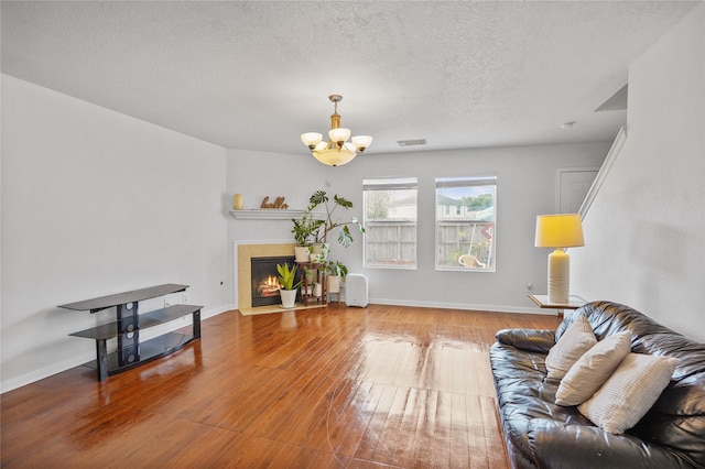 living room featuring hardwood / wood-style flooring, a notable chandelier, and a textured ceiling