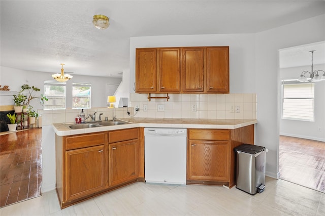 kitchen with white dishwasher, sink, hanging light fixtures, and an inviting chandelier