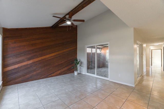 tiled empty room with wood walls, beamed ceiling, high vaulted ceiling, and ceiling fan