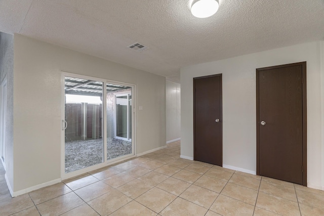 unfurnished room with light tile patterned floors and a textured ceiling