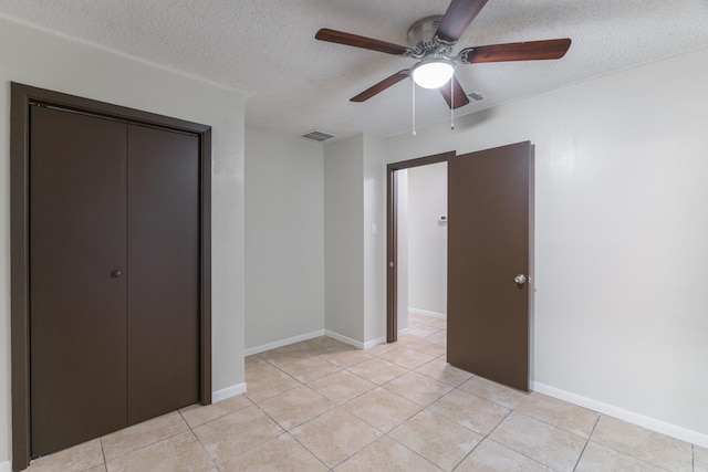 unfurnished bedroom featuring ceiling fan, light tile patterned floors, a textured ceiling, and a closet