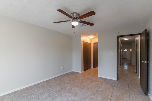 unfurnished bedroom with a textured ceiling, a closet, ceiling fan, and light tile patterned flooring