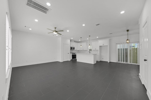 unfurnished living room featuring ceiling fan and dark tile patterned flooring