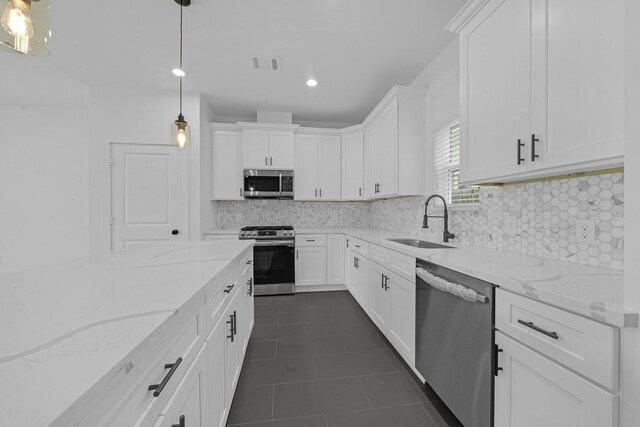 kitchen featuring appliances with stainless steel finishes, backsplash, sink, white cabinetry, and hanging light fixtures