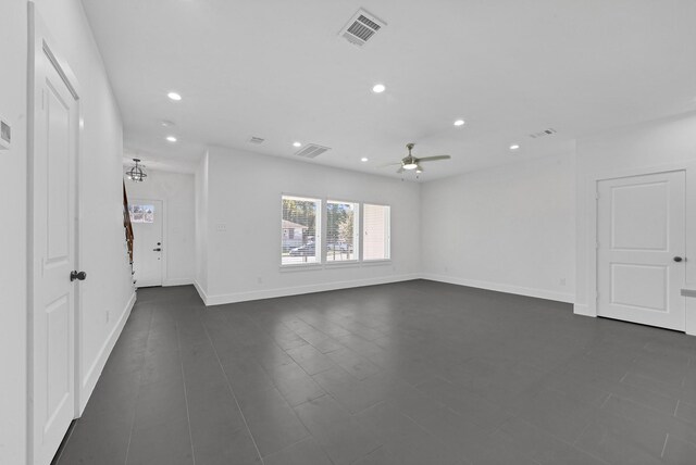 spare room featuring ceiling fan with notable chandelier