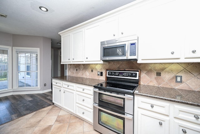 kitchen featuring dark stone countertops, white cabinetry, and stainless steel appliances