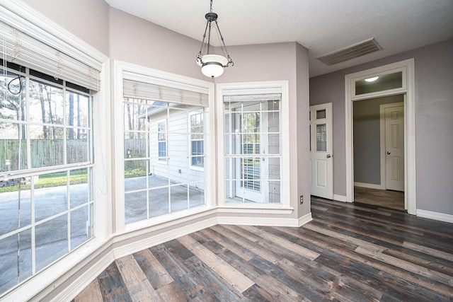 unfurnished dining area with dark wood-type flooring